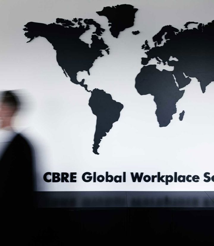 Medarbejder på CBRE kontor, hvor der er verdenskort i baggrunden som viser, CBRE arbejder i hele verdenen