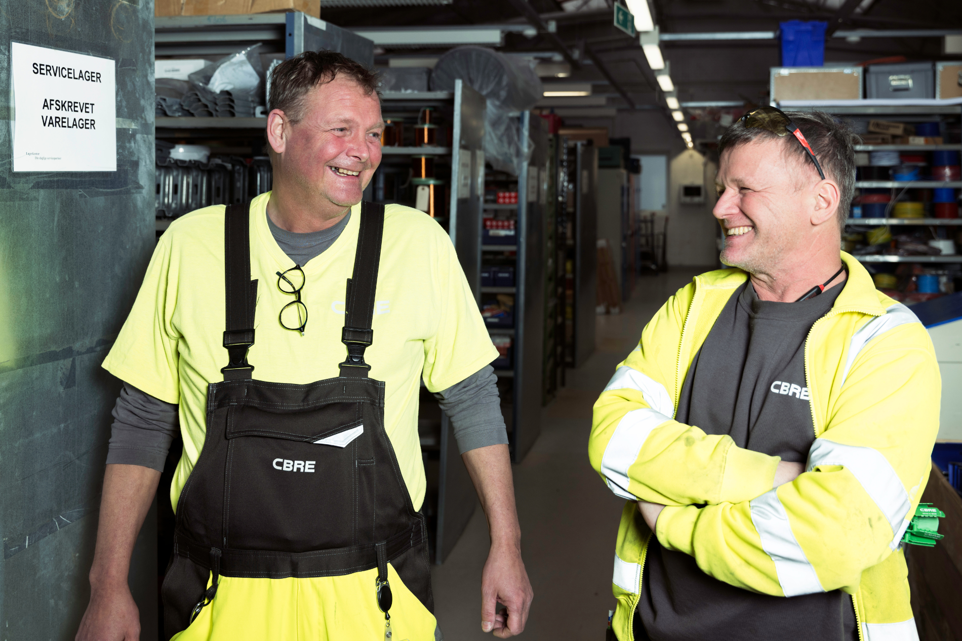 To CBRE elektrikere arbejder på et lager i en bygning