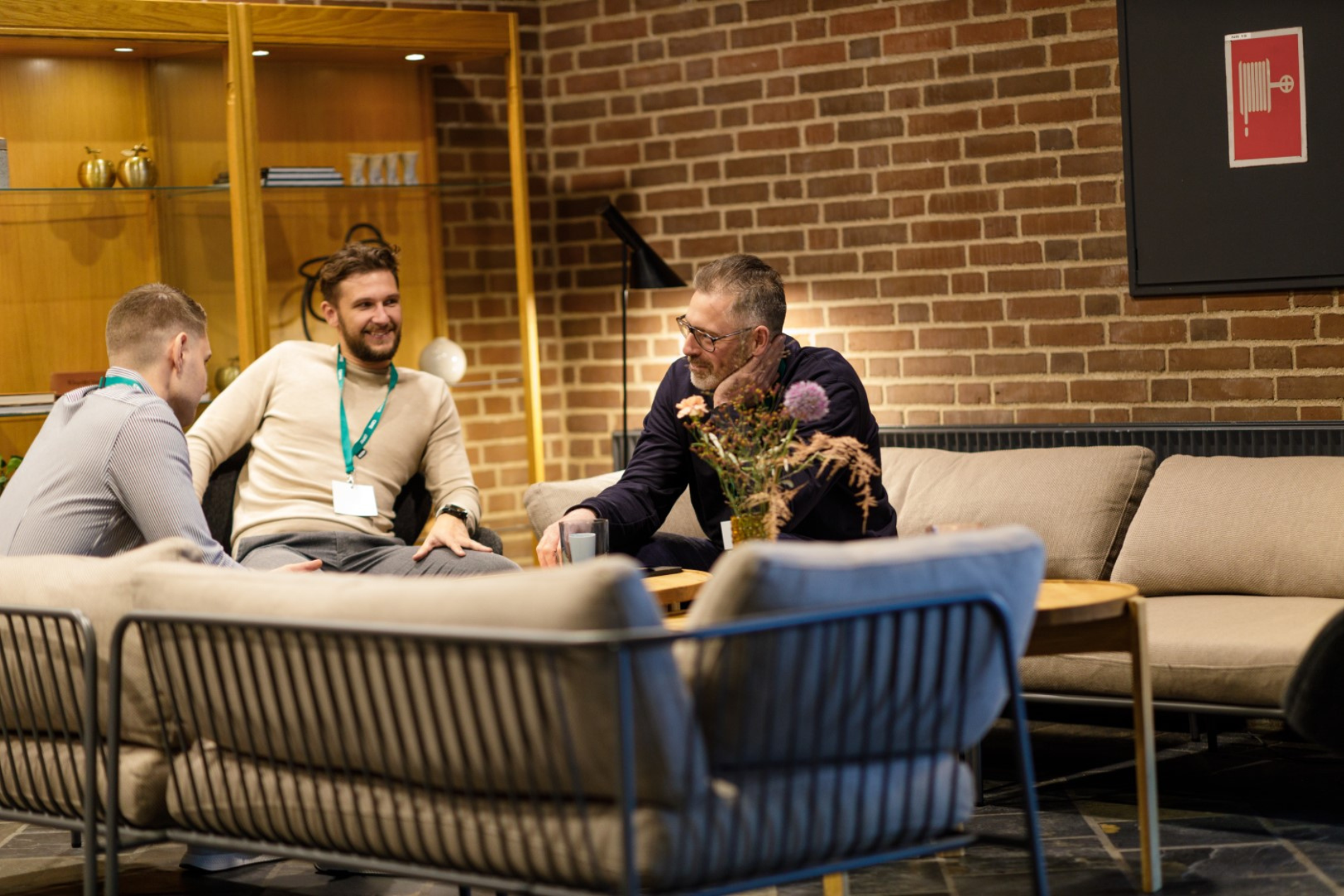 Tre kollegaer sidder og snakker sammen i en sofa